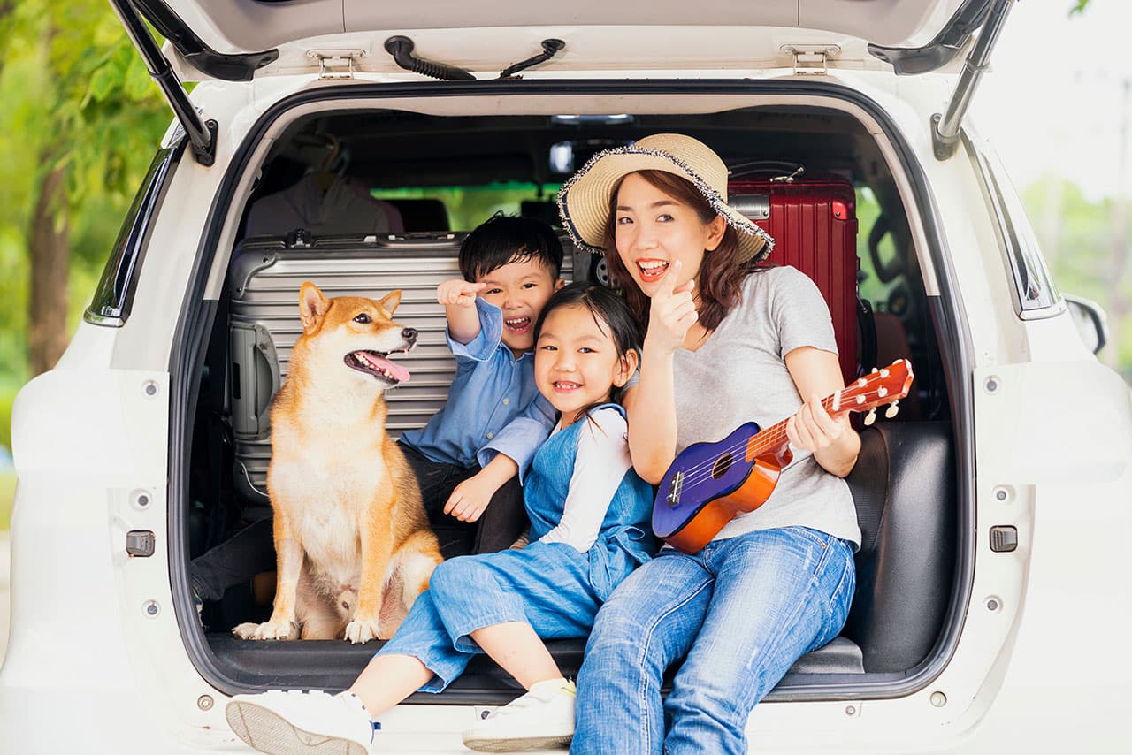 家族と愛犬が車の後ろに座って笑顔の様子